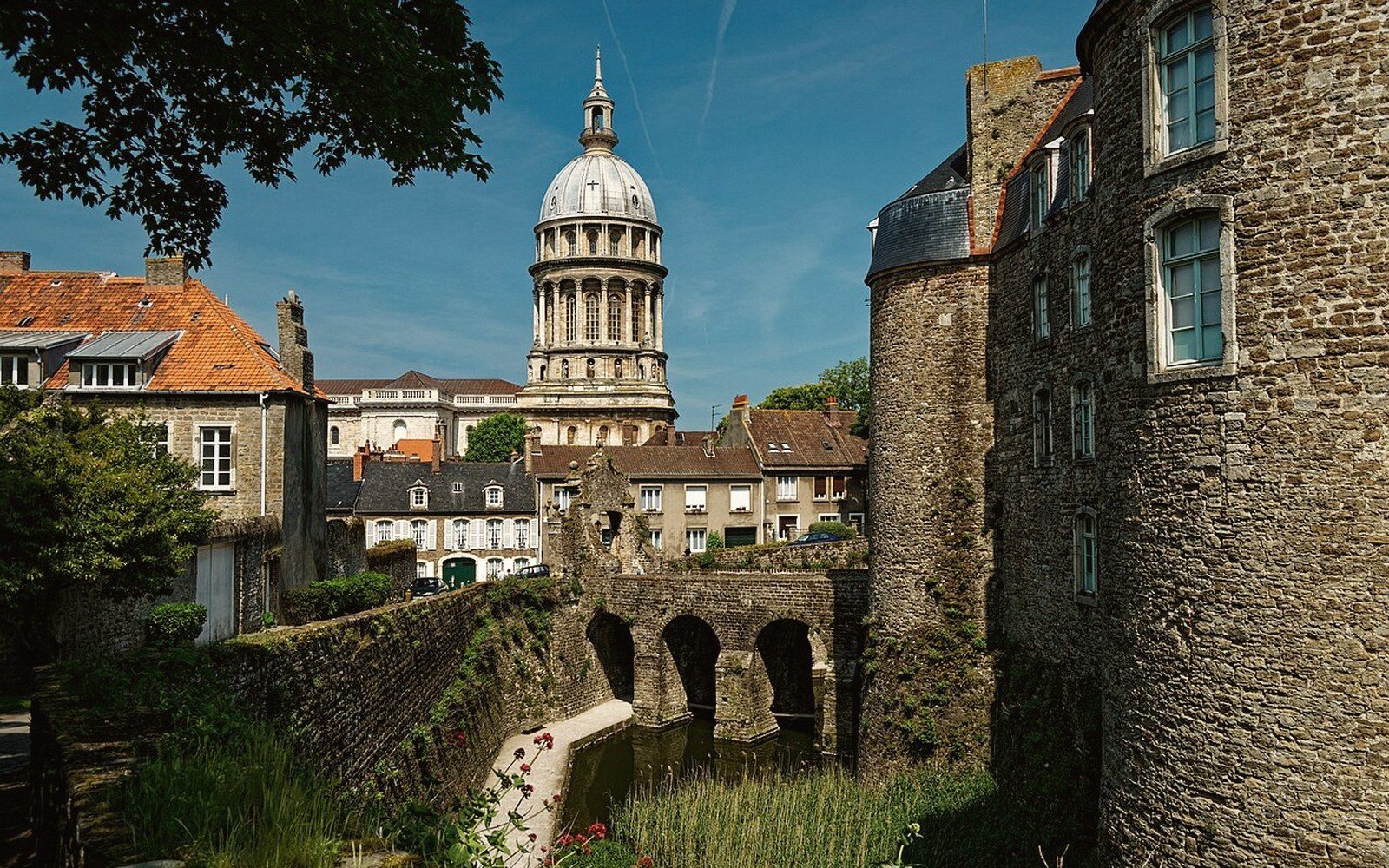 Domed basilica rises above a stone ramparts and arched bridge in Boulogne-sur-Mer's old town
